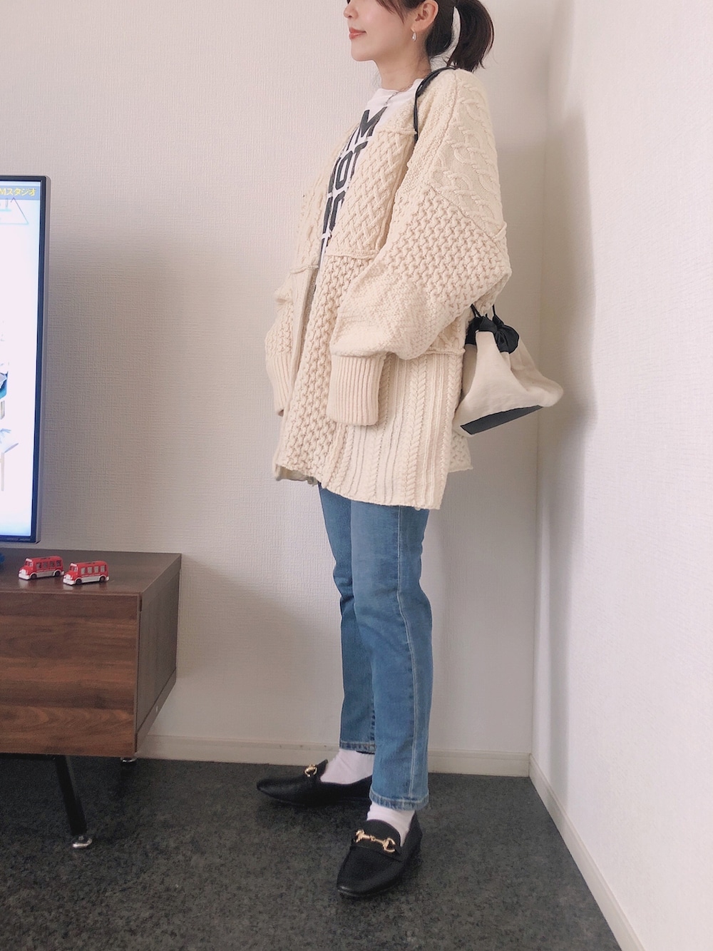 ホワイト系のカーディガン/ボレロ、ホワイト系のTシャツ/カットソー、ブラック系のローファーを着用したレディースの冬コーディネートの4枚目の写真