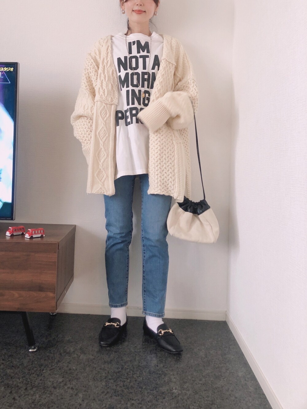 ホワイト系のカーディガン/ボレロ、ホワイト系のTシャツ/カットソー、ブラック系のローファーを着用したレディースの冬コーディネートの3枚目の写真