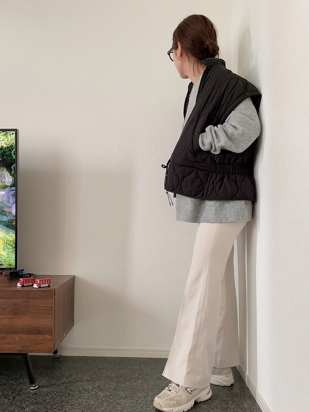 ブラック系のダウンベスト、グレー系のニット/セーター、ホワイト系のパンツを着用したレディースの秋コーディネートの3枚目の写真