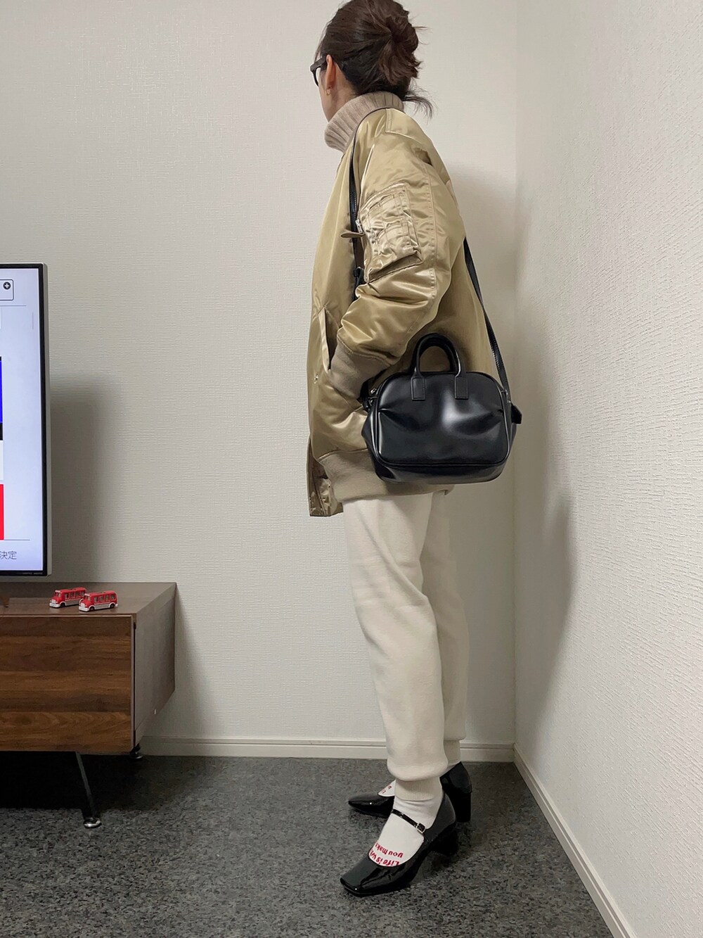 ベージュ系のダウンジャケット/コート、ベージュ系のニット/セーター、ブラック系のショルダーバッグを着用したレディースの冬コーディネートの2枚目の写真