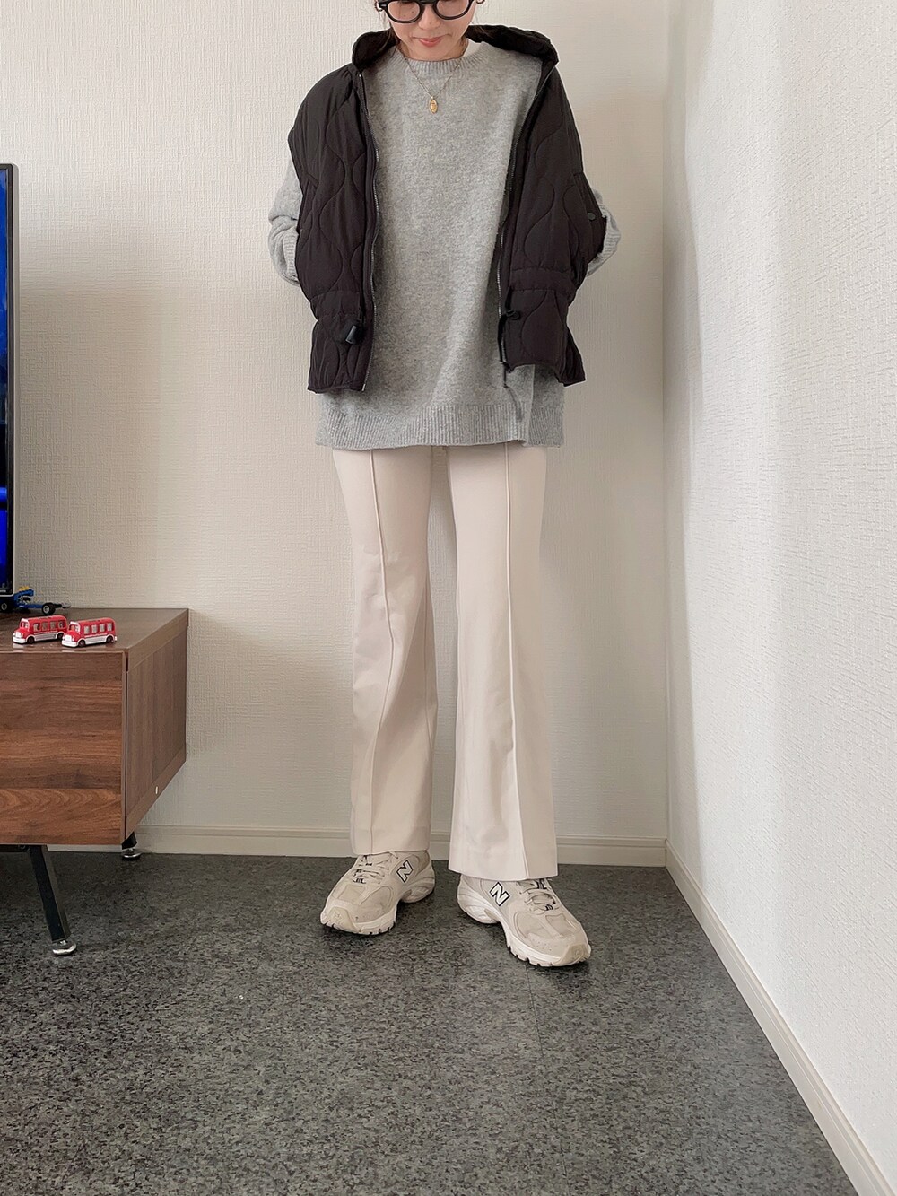ブラック系のダウンベスト、グレー系のニット/セーター、ホワイト系のパンツを着用したレディースの秋コーディネートの2枚目の写真