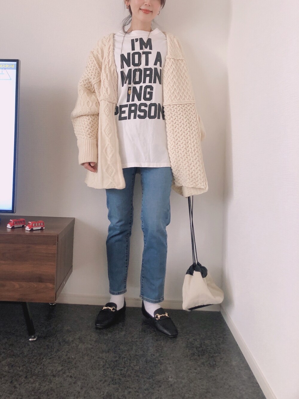 ホワイト系のカーディガン/ボレロ、ホワイト系のTシャツ/カットソー、ブラック系のローファーを着用したレディースの冬コーディネートの2枚目の写真