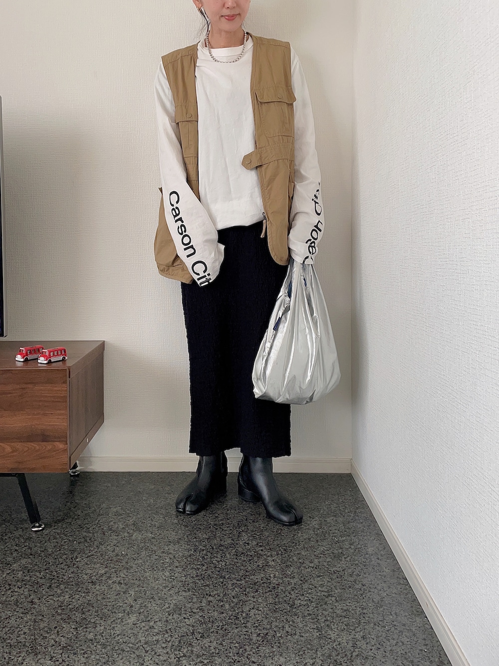 ホワイト系のTシャツ/カットソー、ベージュ系のベスト、シルバー系のショルダーバッグを着用したレディースの春コーディネートの2枚目の写真