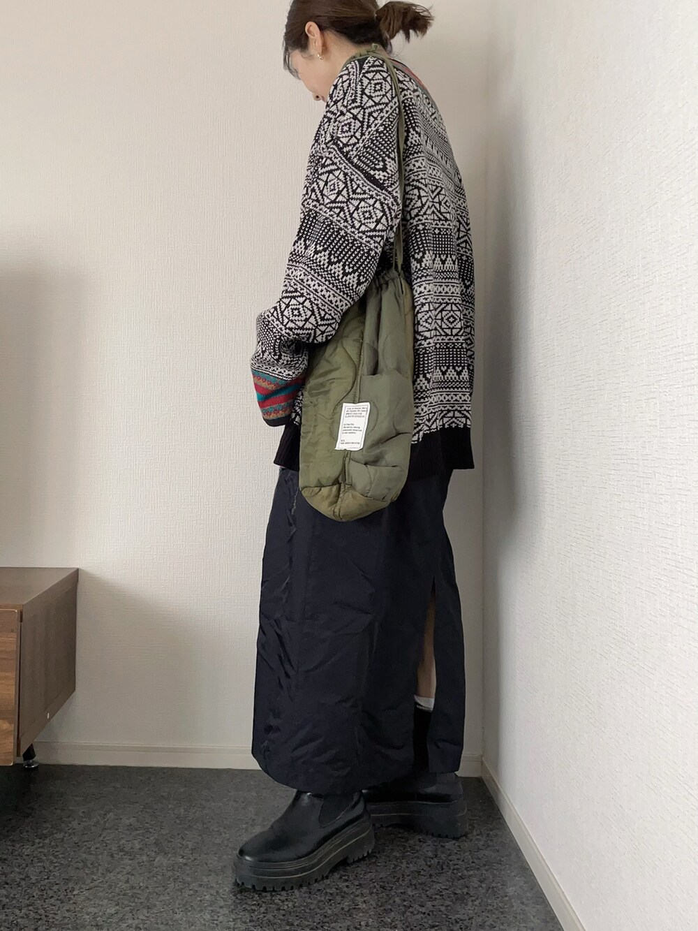 ブラック系のカーディガン/ボレロ、ブラック系のジャンパースカート、グリーン系のショルダーバッグを着用したレディースの春コーディネートの2枚目の写真