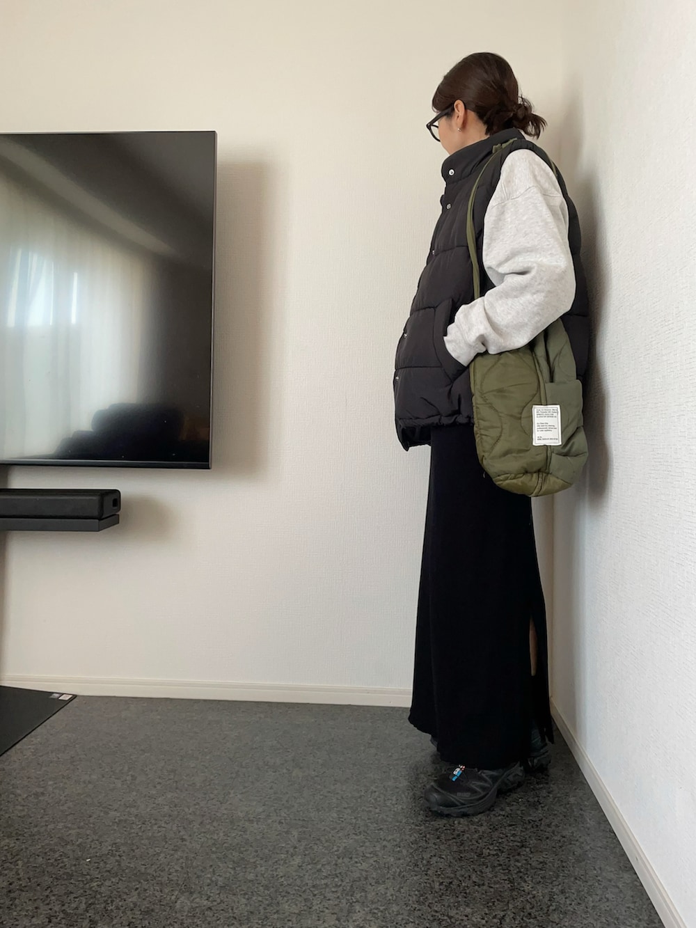 ブラック系のダウンベスト、グレー系のスウェット、グリーン系のショルダーバッグを着用したレディースの冬コーディネートの3枚目の写真