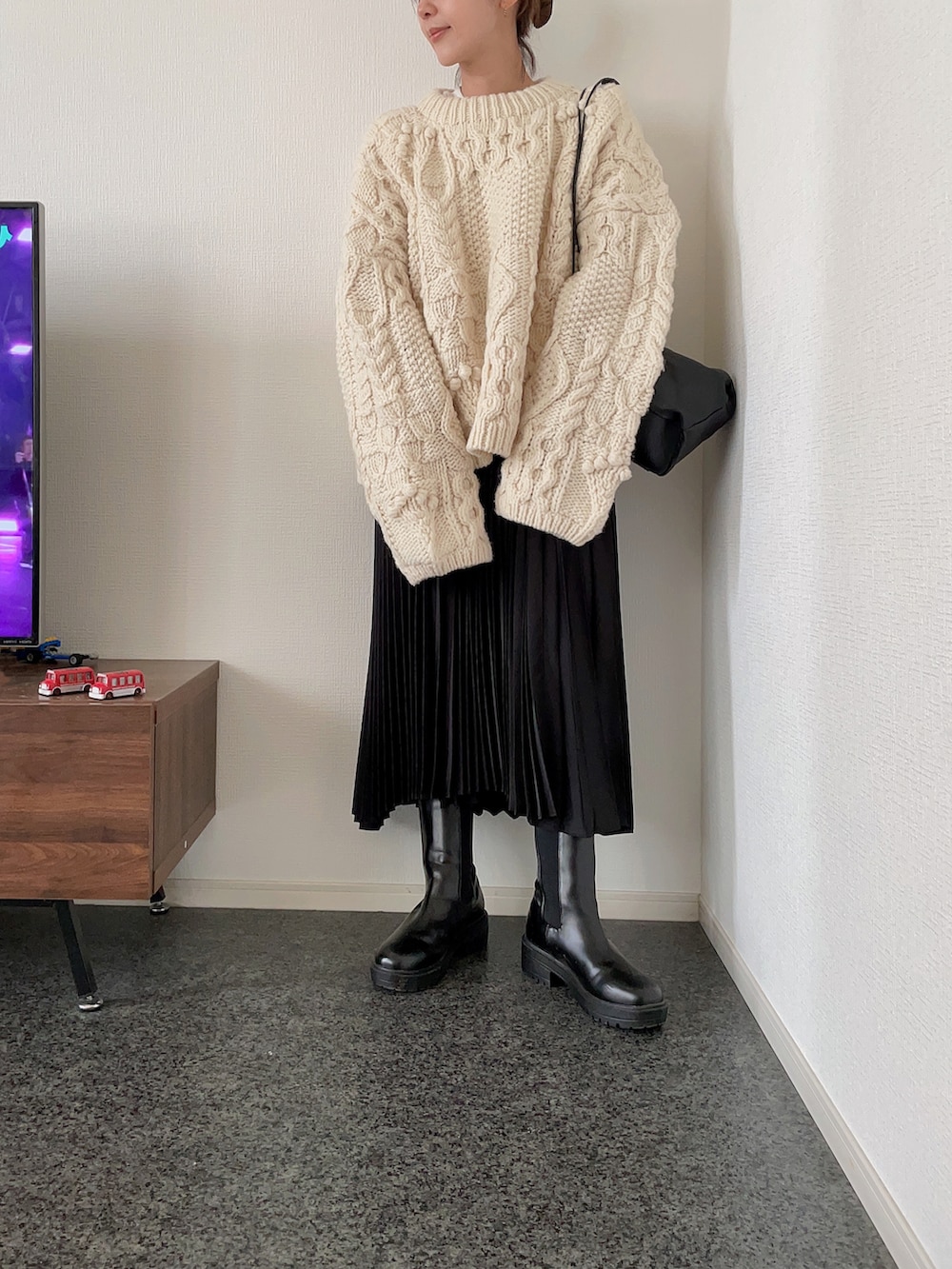 ホワイト系のニット/セーター、ブラック系のスカート、ブラック系のブーツを着用したレディースの秋コーディネートの2枚目の写真