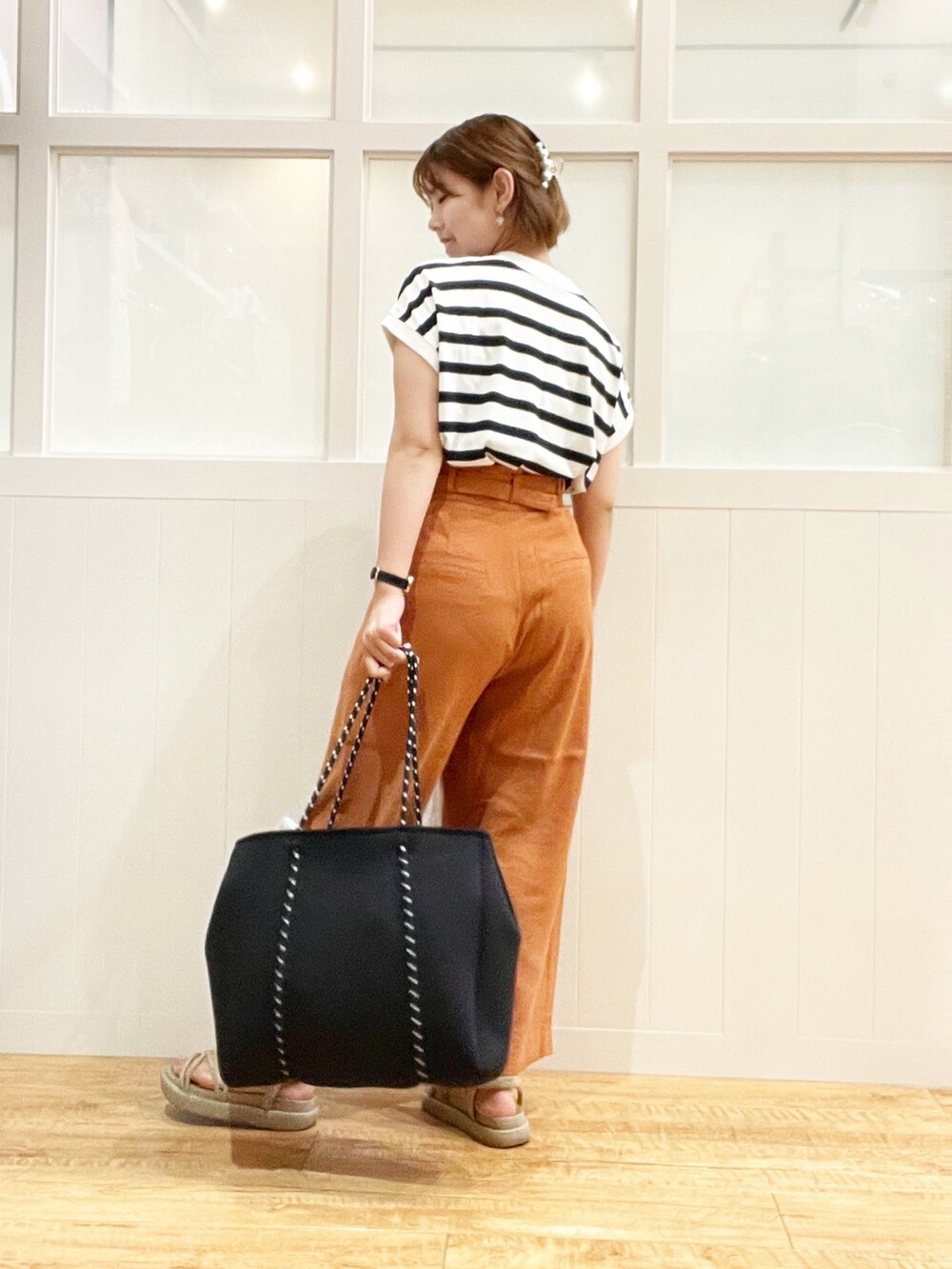 ブラック系のトートバッグ、ブラック系のトップス、オレンジ系のパンツを着用したレディースの夏コーディネートの2枚目の写真