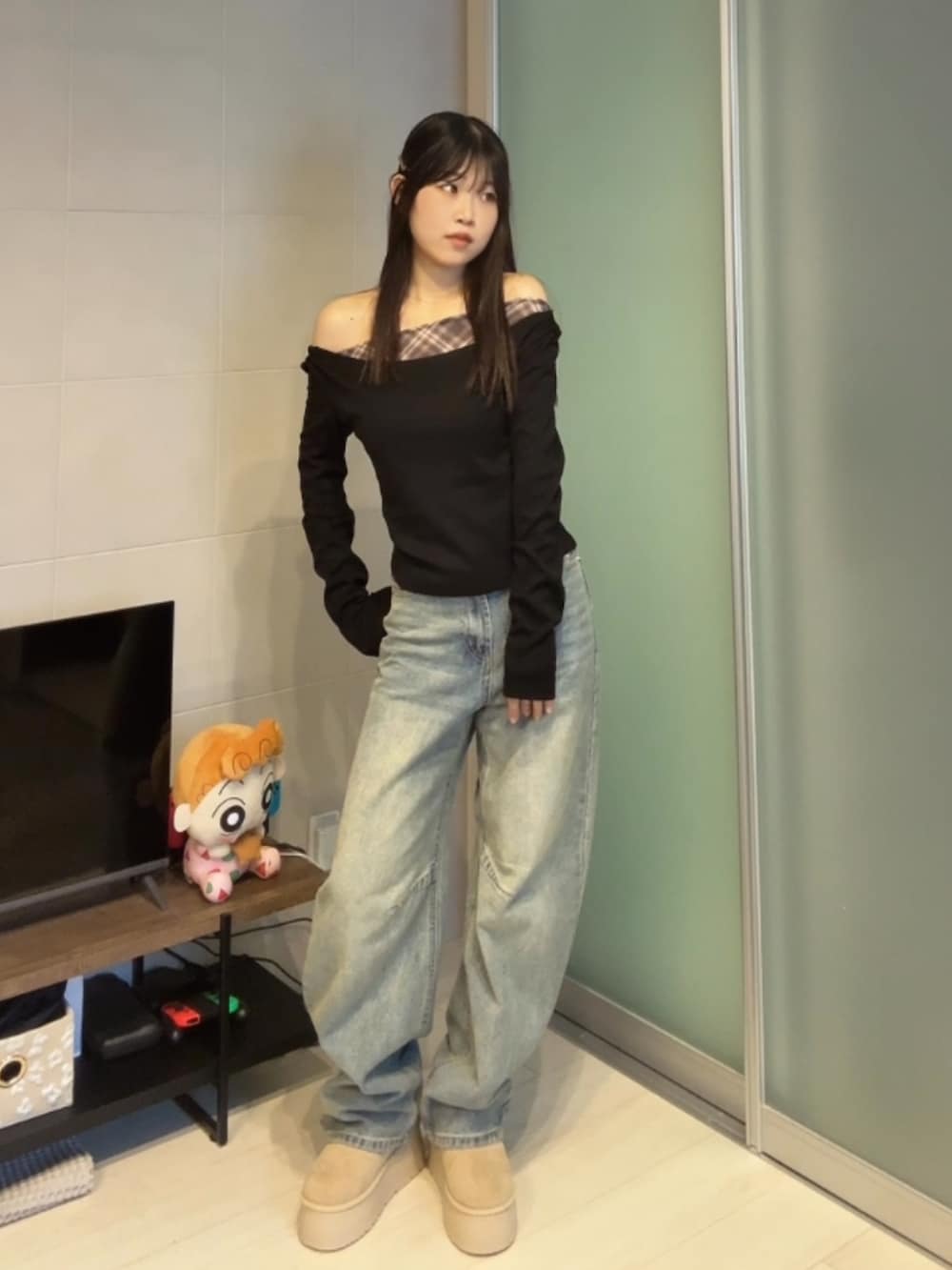 ブラック系のトップス、ブルー系のデニムパンツ、ベージュ系のブーツを着用したレディースの冬コーディネートの2枚目の写真