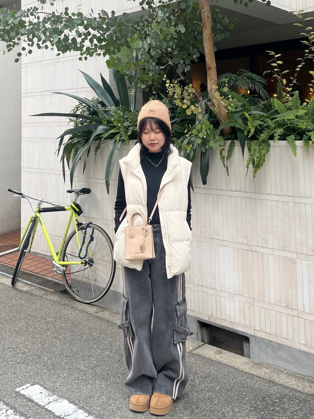 ブラック系のデニムパンツ、ベージュ系のブーツ、ホワイト系のダウンベストを着用したレディースの冬コーディネートの3枚目の写真