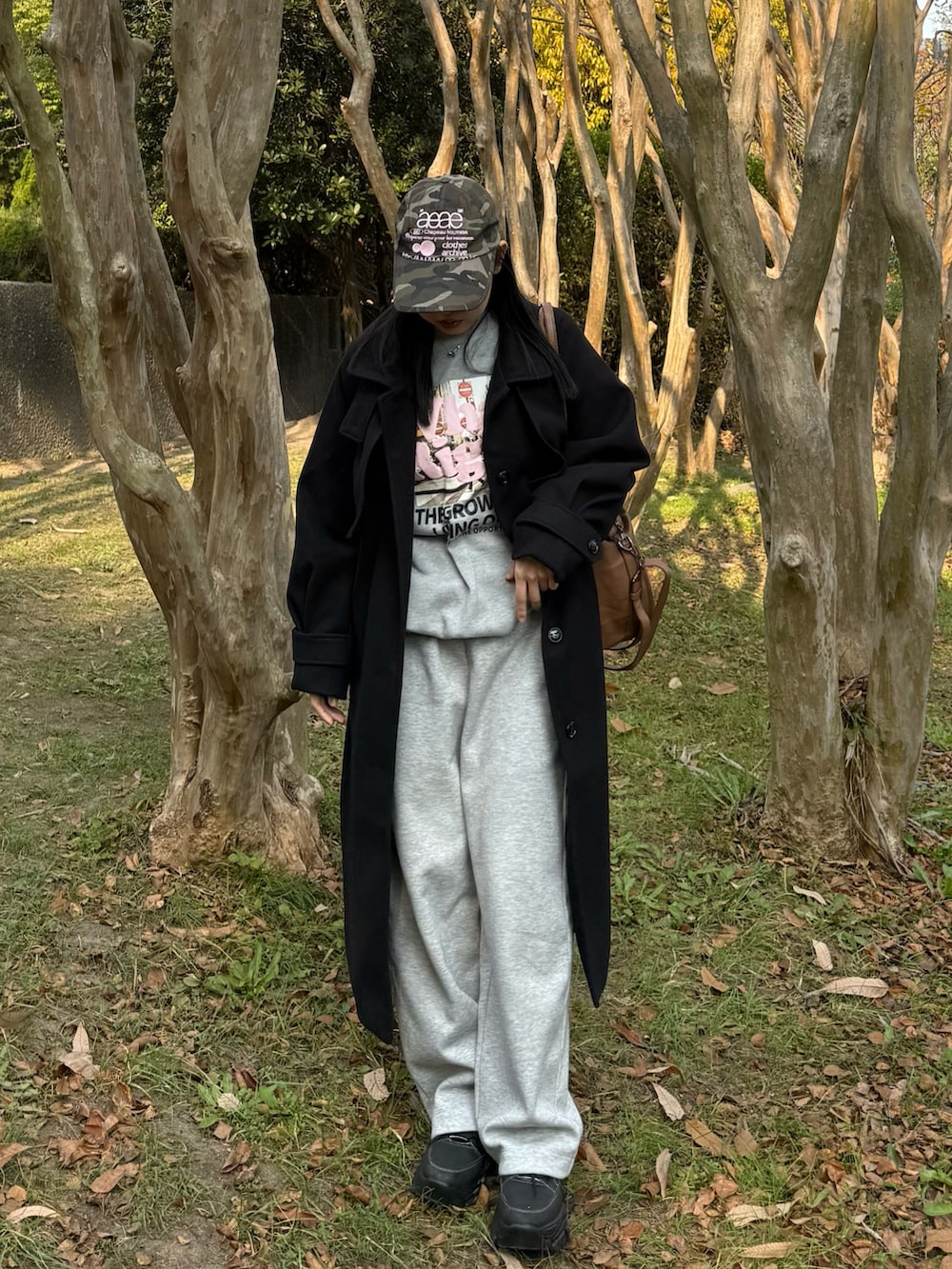 ブラウン系のボストンバッグ、ブラック系のその他アウター、ブラック系のスニーカーを着用したレディースの冬コーディネートの2枚目の写真