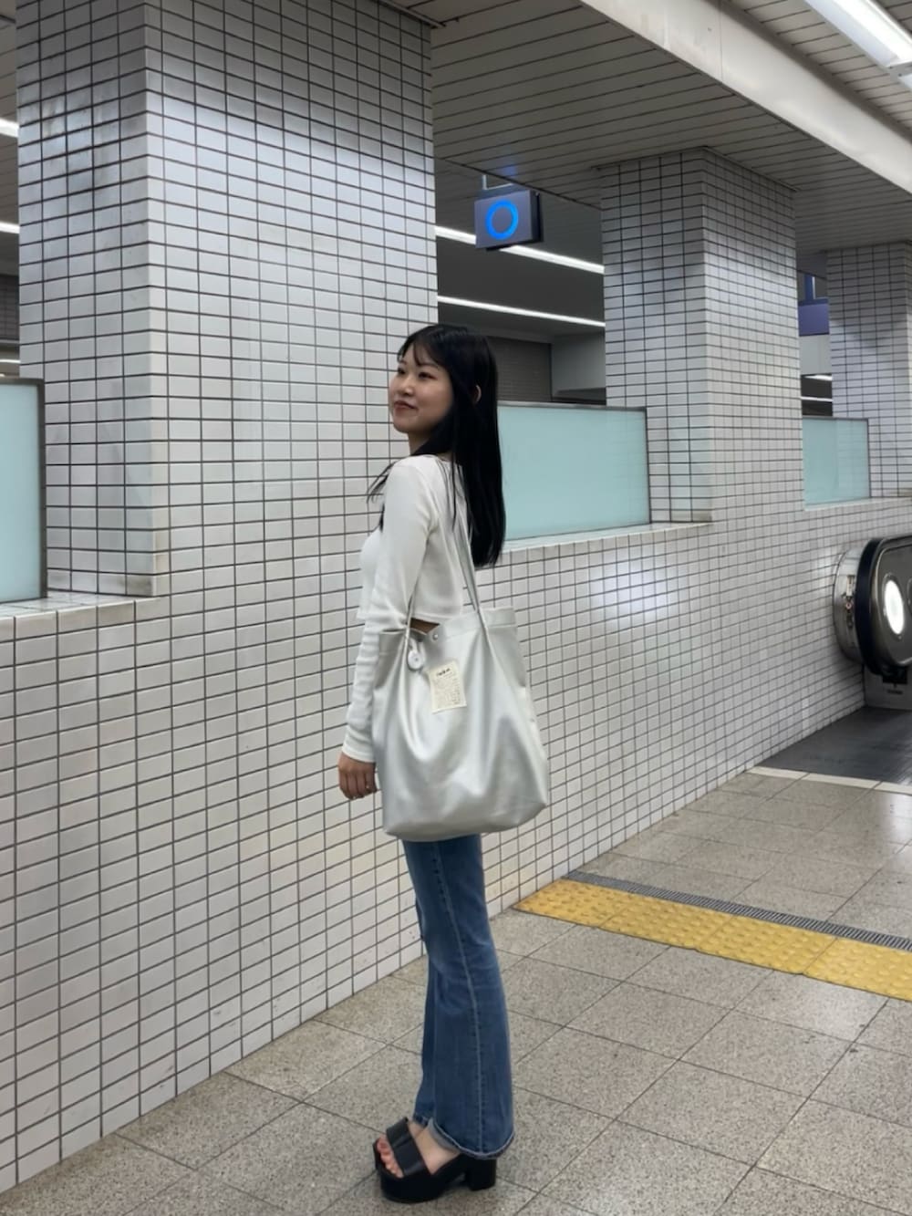 ブルー系のデニムパンツ、ホワイト系のTシャツ/カットソー、シルバー系のトートバッグを着用したレディースの秋コーディネートの3枚目の写真