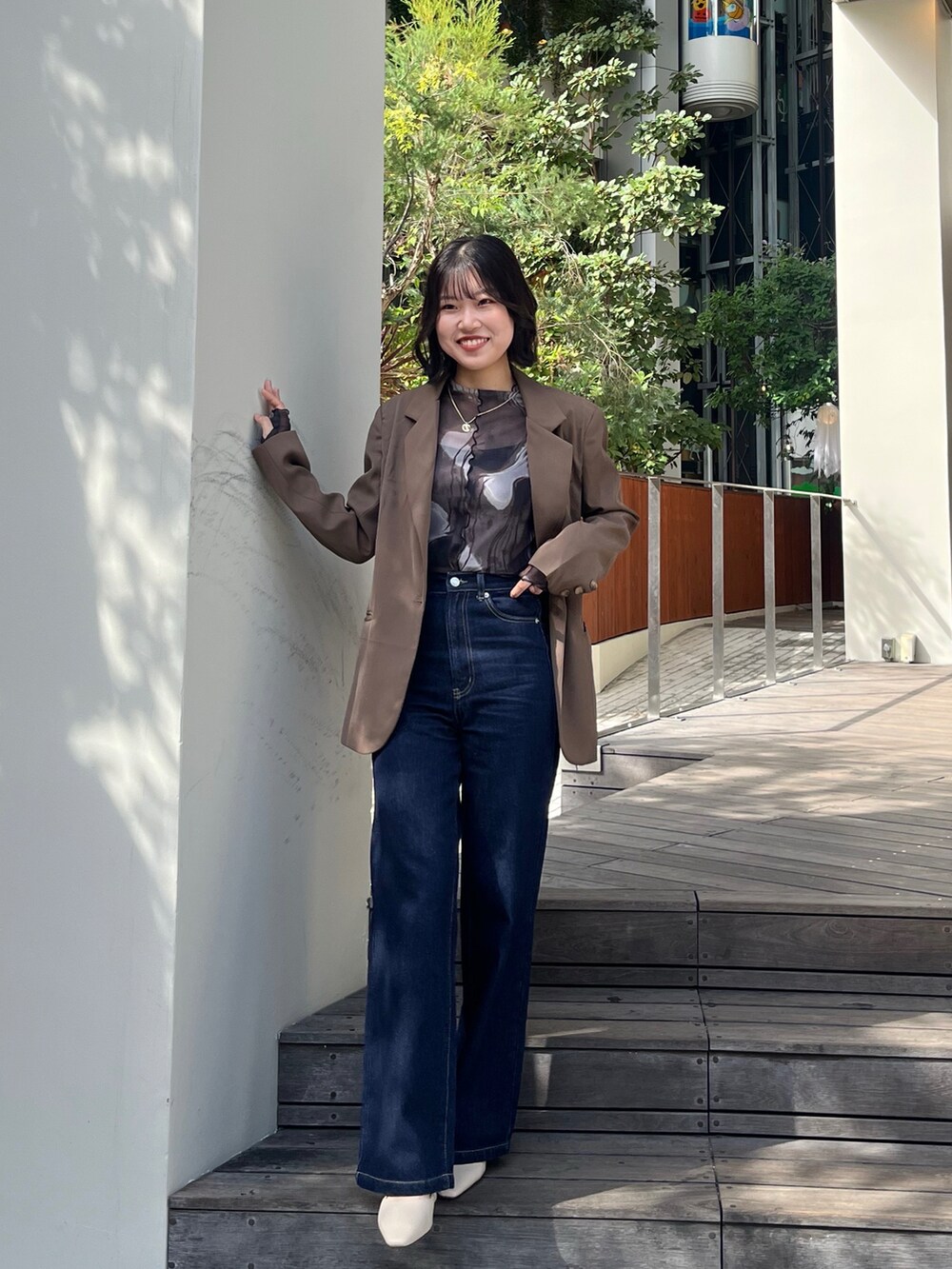 ブルー系のデニムパンツ、ブラック系のパンプス、グリーン系のTシャツ/カットソーを着用したレディースの秋コーディネートの2枚目の写真