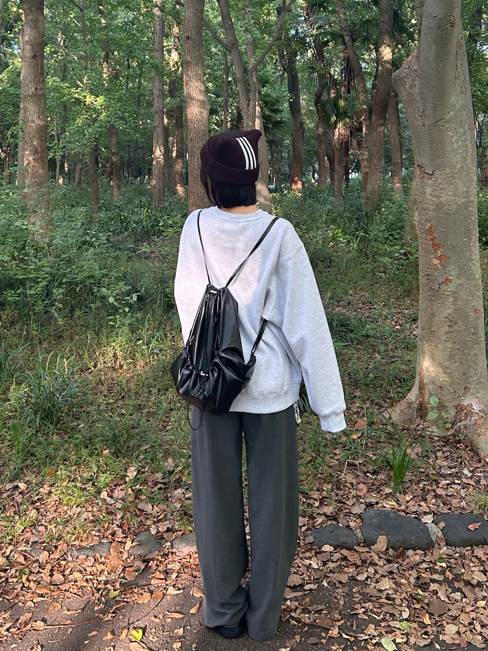 グレー系のスラックス、ブラック系のバックパック/リュック、ブラック系のスウェットを着用したレディースの秋コーディネートの3枚目の写真