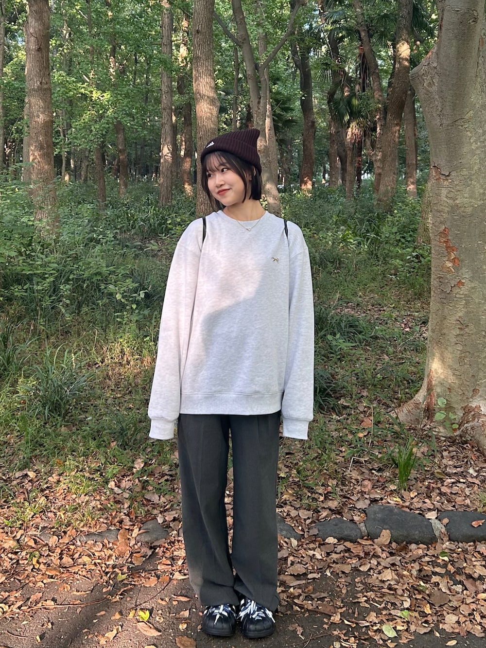 グレー系のスラックス、ブラック系のバックパック/リュック、ブラック系のスウェットを着用したレディースの秋コーディネートの2枚目の写真