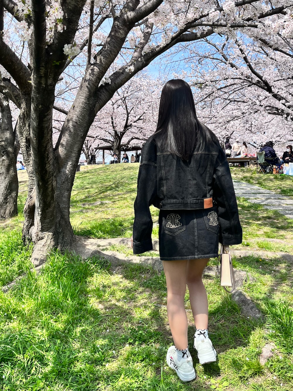 ベージュ系のショルダーバッグ、ブラック系のデニムジャケット、ブラック系のデニムスカートを着用したレディースの春コーディネートの4枚目の写真