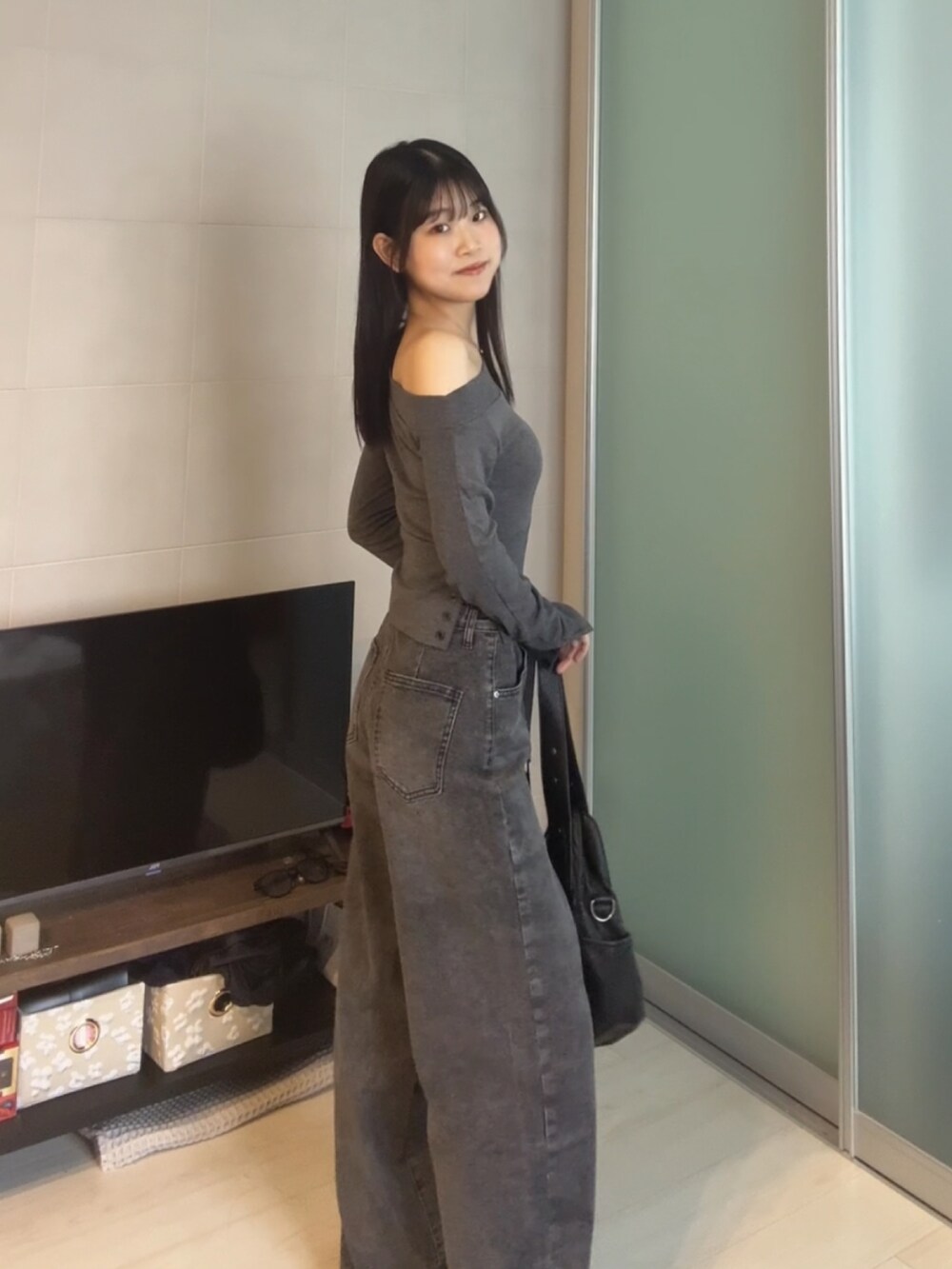 ブラック系のデニムパンツ、グレー系のTシャツ/カットソー、ブラック系のショルダーバッグを着用したレディースの秋コーディネートの2枚目の写真