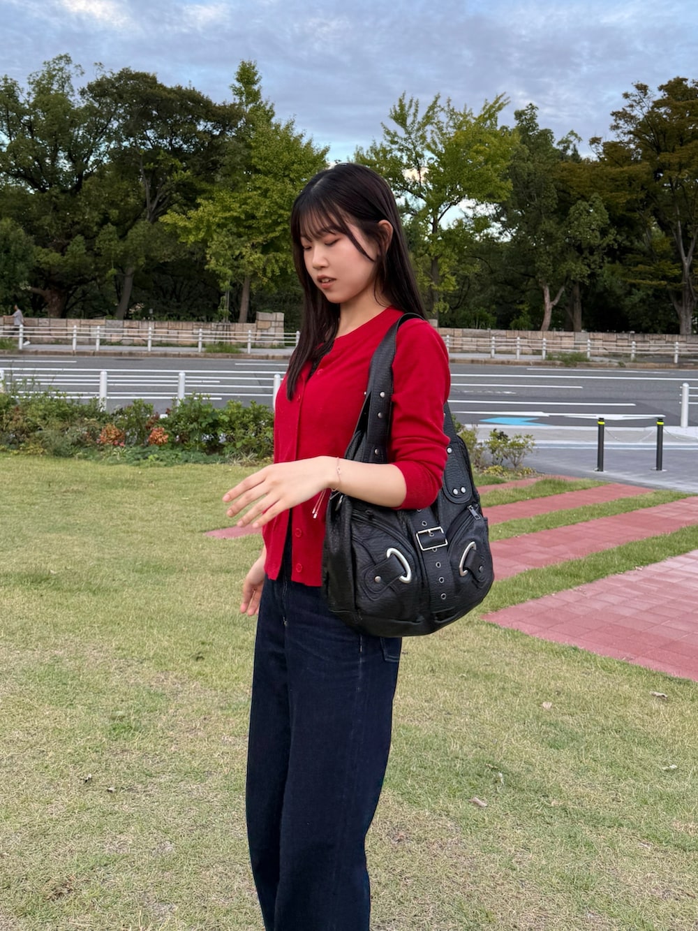 ブルー系のデニムパンツ、レッド系のカーディガン/ボレロ、ブラック系のショルダーバッグを着用したレディースの秋コーディネートの2枚目の写真