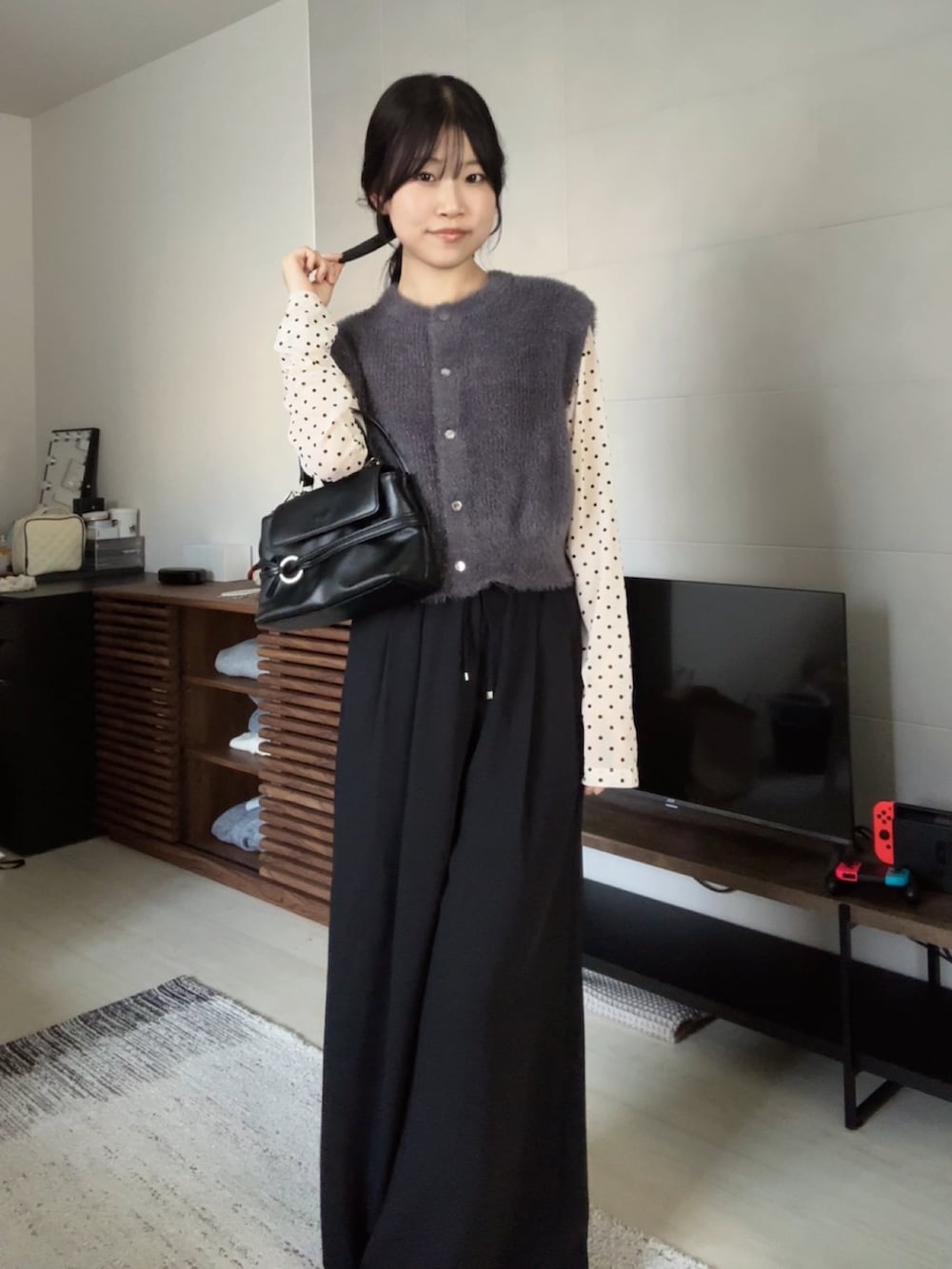 グレー系のベスト、ベージュ系のTシャツ/カットソー、ブラック系のショルダーバッグを着用したレディースの秋コーディネートの2枚目の写真