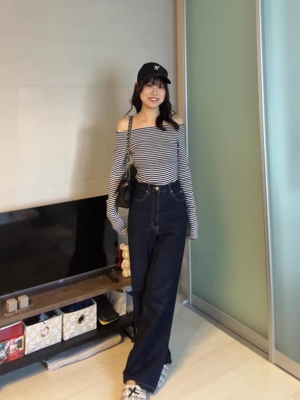 ブルー系のデニムパンツ、ブラック系のTシャツ/カットソー、ブラック系のショルダーバッグを着用したレディースの秋コーディネートの2枚目の写真