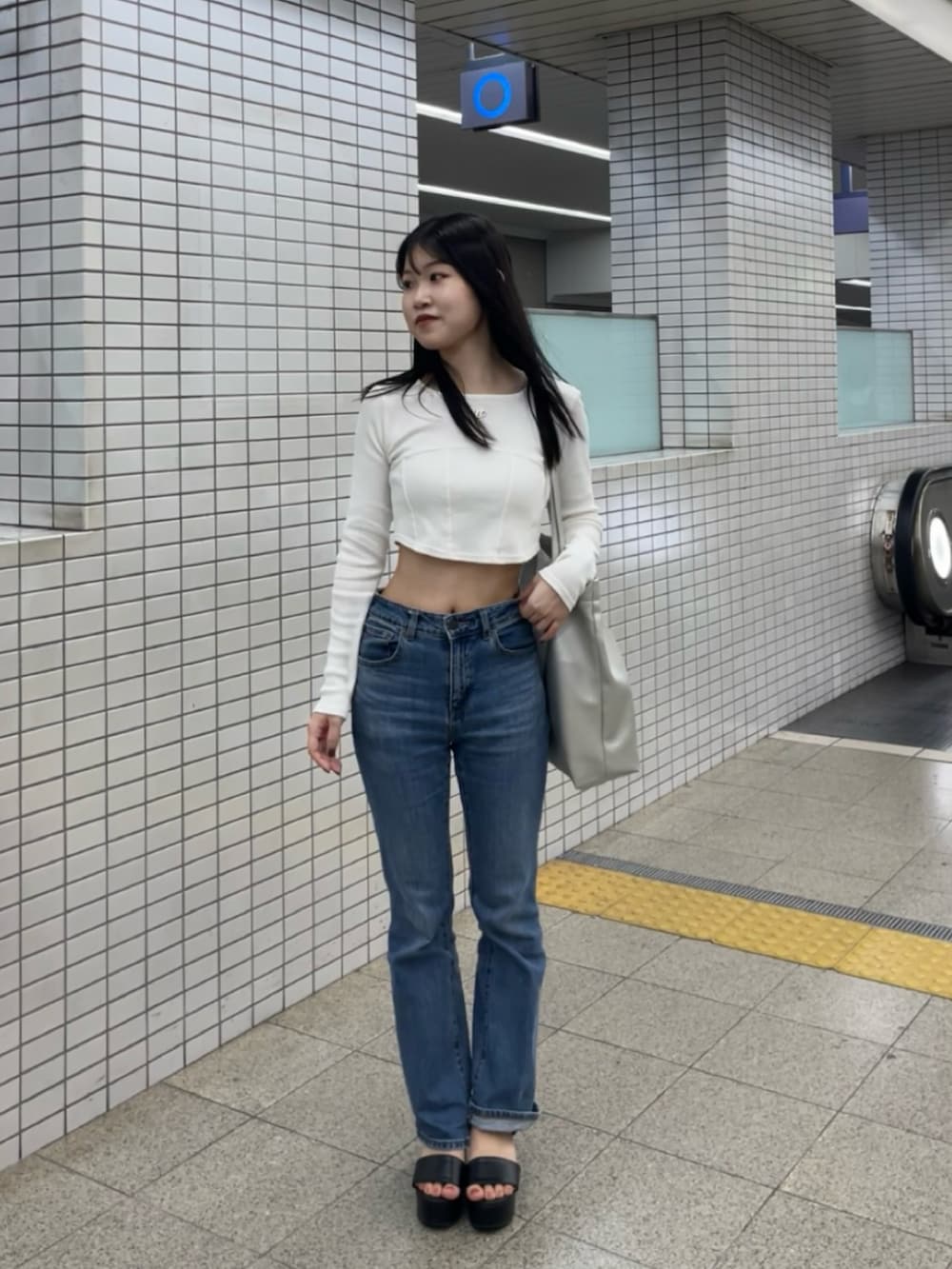 ブルー系のデニムパンツ、ホワイト系のTシャツ/カットソー、シルバー系のトートバッグを着用したレディースの秋コーディネートの2枚目の写真