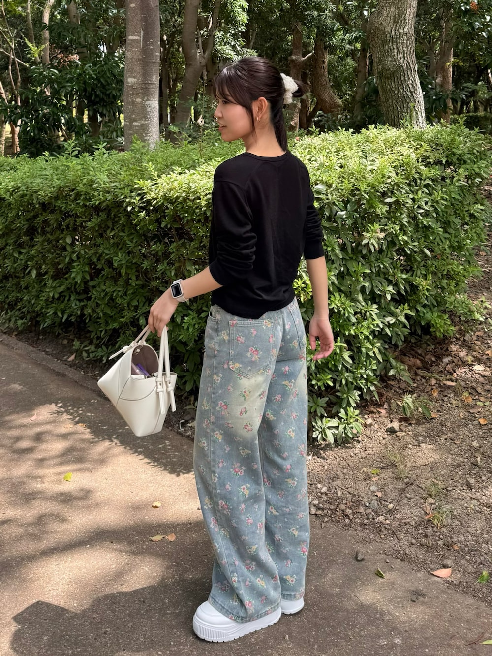 ブルー系のデニムパンツ、ホワイト系のハンドバッグ、ブラック系のカーディガン/ボレロを着用したレディースの夏コーディネートの2枚目の写真