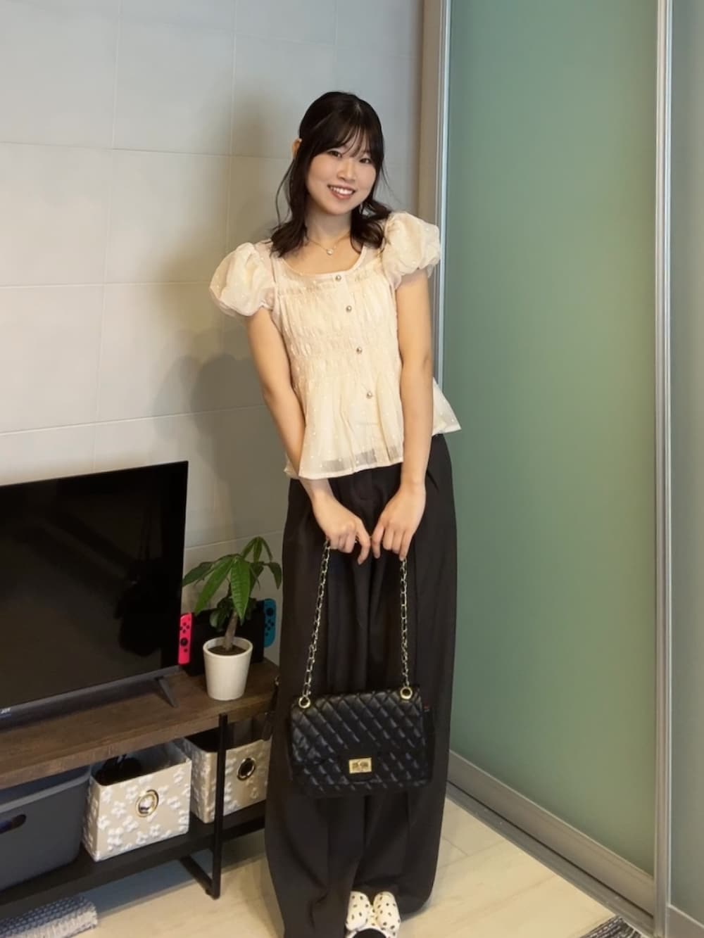 ピンク系のシャツ/ブラウス、グレー系のスラックス、ブラック系のショルダーバッグを着用したレディースの春コーディネートの3枚目の写真