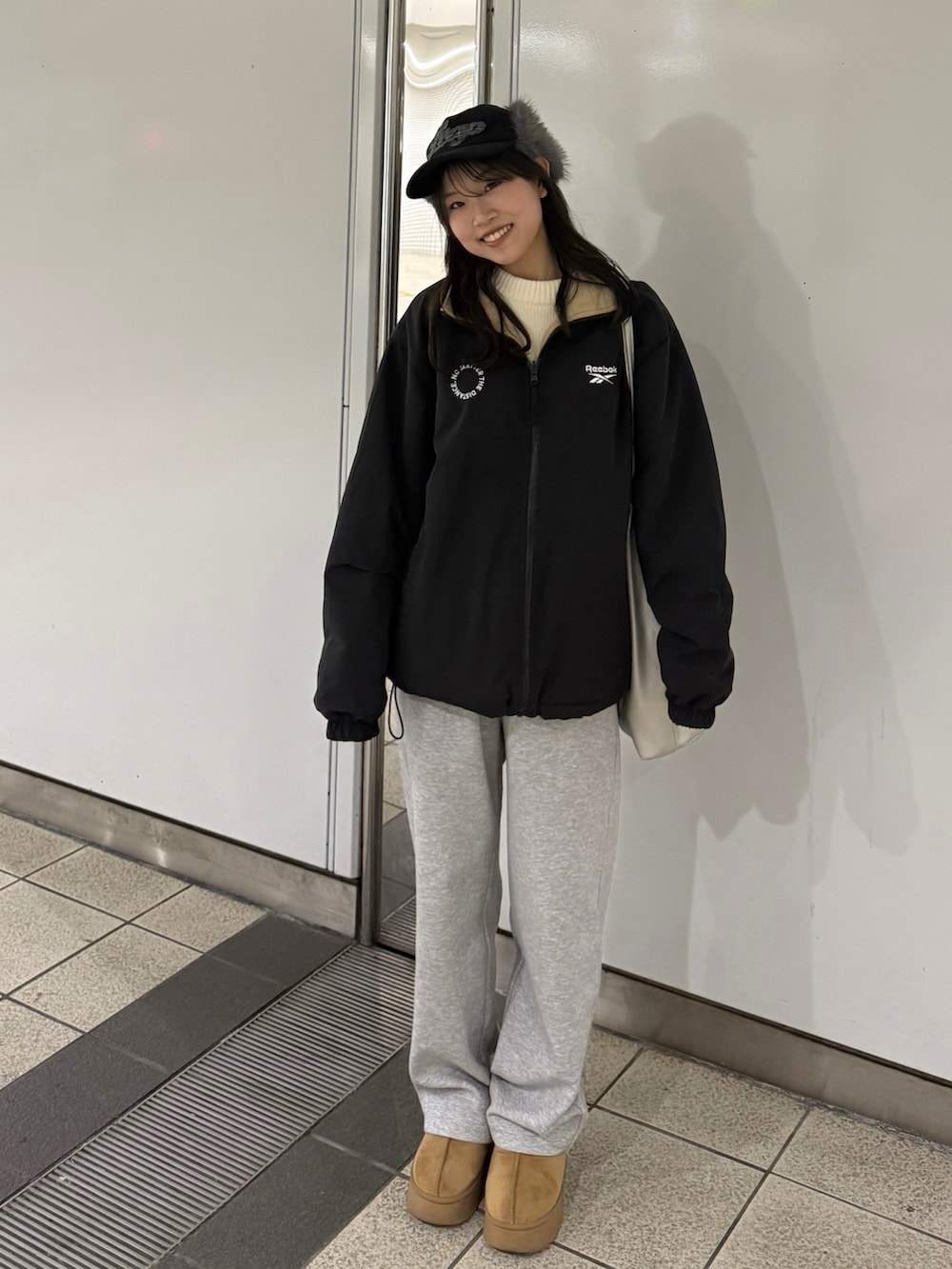 シルバー系のトートバッグ、グレー系のスウェットパンツ、ベージュ系のブーツを着用したレディースの冬コーディネートの2枚目の写真