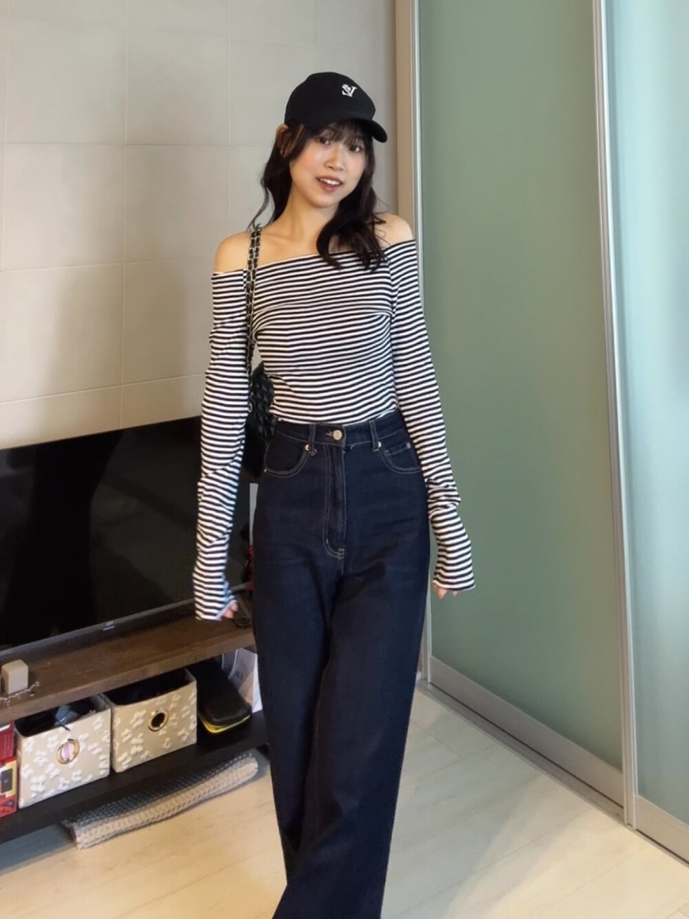 ブルー系のデニムパンツ、ブラック系のTシャツ/カットソー、ブラック系のショルダーバッグを着用したレディースの秋コーディネートの4枚目の写真