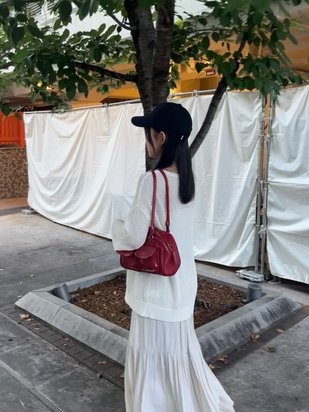 ホワイト系のニット/セーター、ホワイト系のスカート、ホワイト系のスニーカーを着用したレディースの夏コーディネートの2枚目の写真