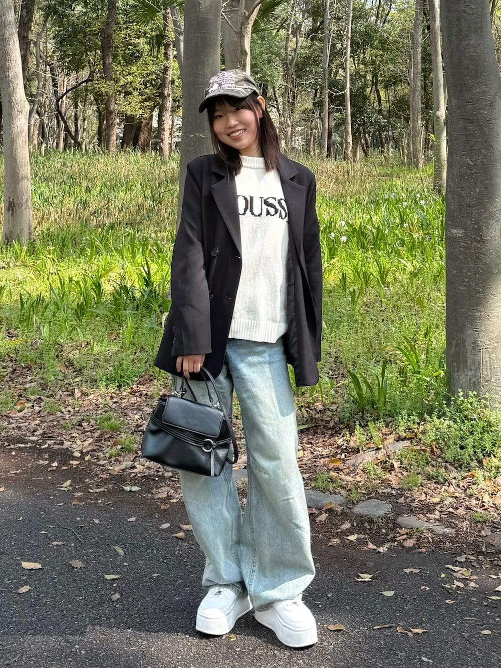 ブラック系のテーラードジャケット、ホワイト系のニット/セーター、ブラック系のショルダーバッグを着用したレディースの春コーディネートの3枚目の写真