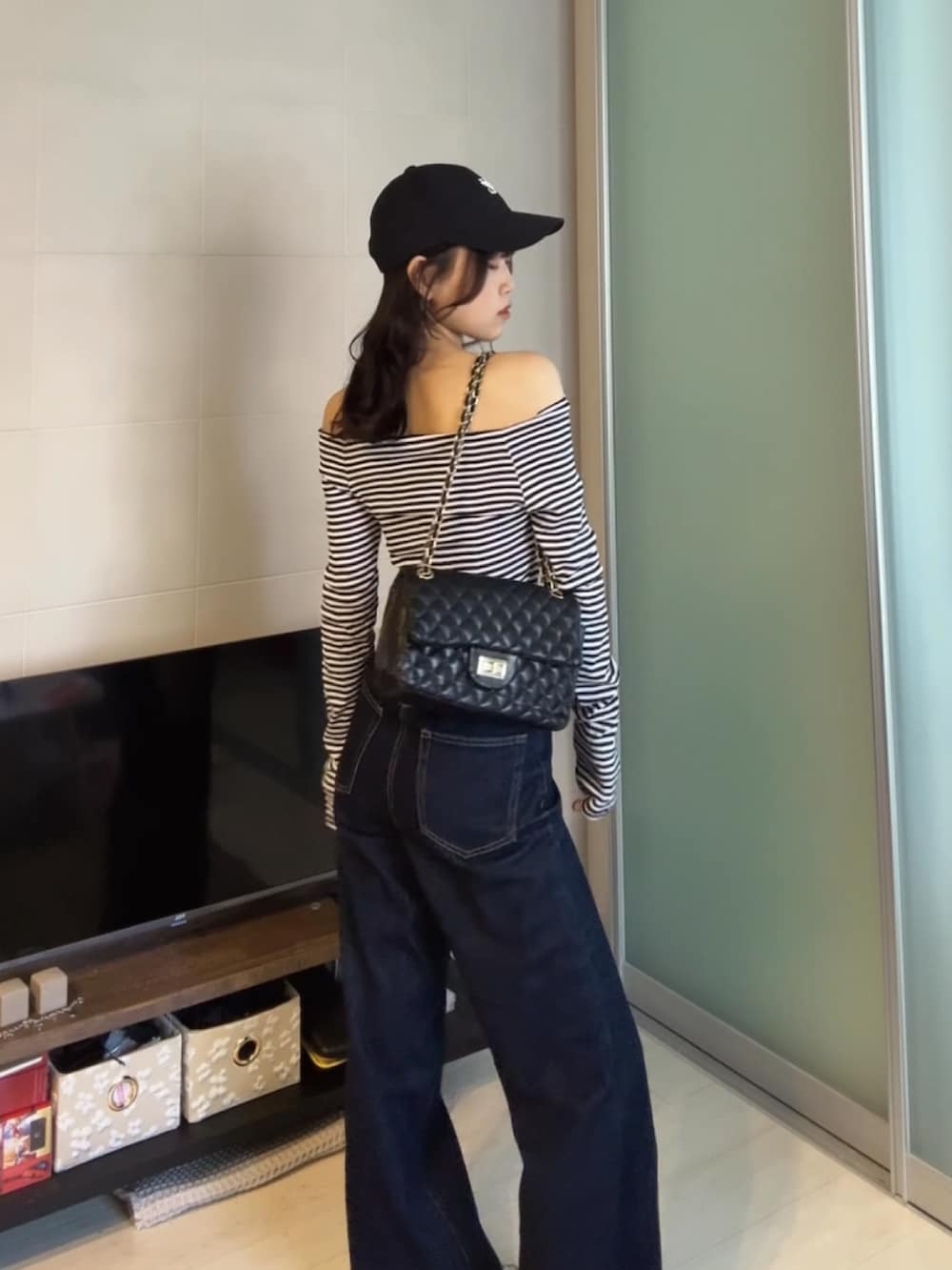 ブルー系のデニムパンツ、ブラック系のTシャツ/カットソー、ブラック系のショルダーバッグを着用したレディースの秋コーディネートの3枚目の写真