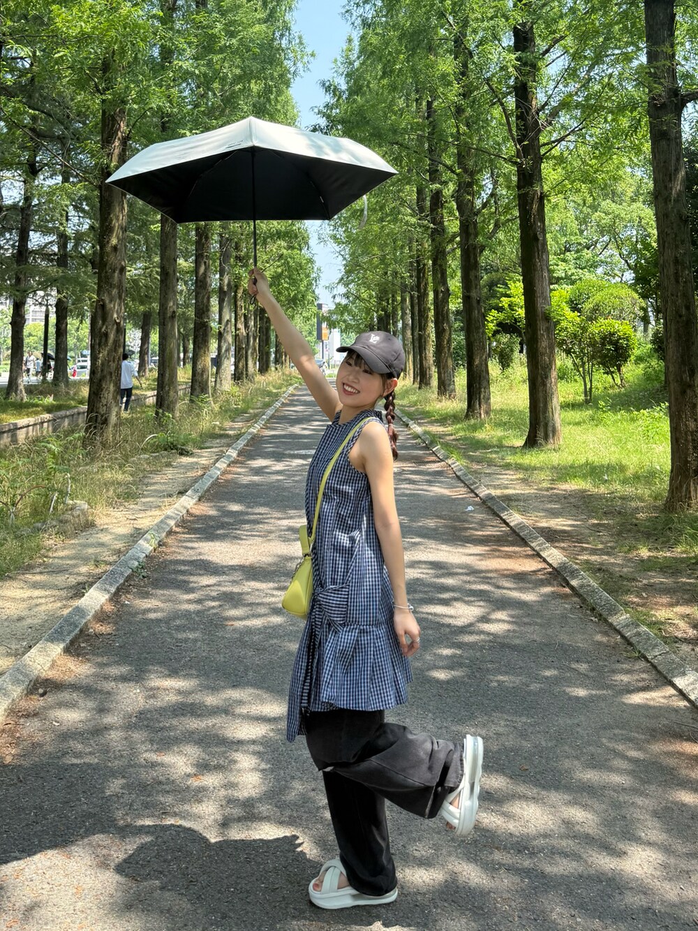 ホワイト系のサンダル、ブラック系のデニムパンツ、イエロー系のトートバッグを着用したレディースの夏コーディネートの2枚目の写真