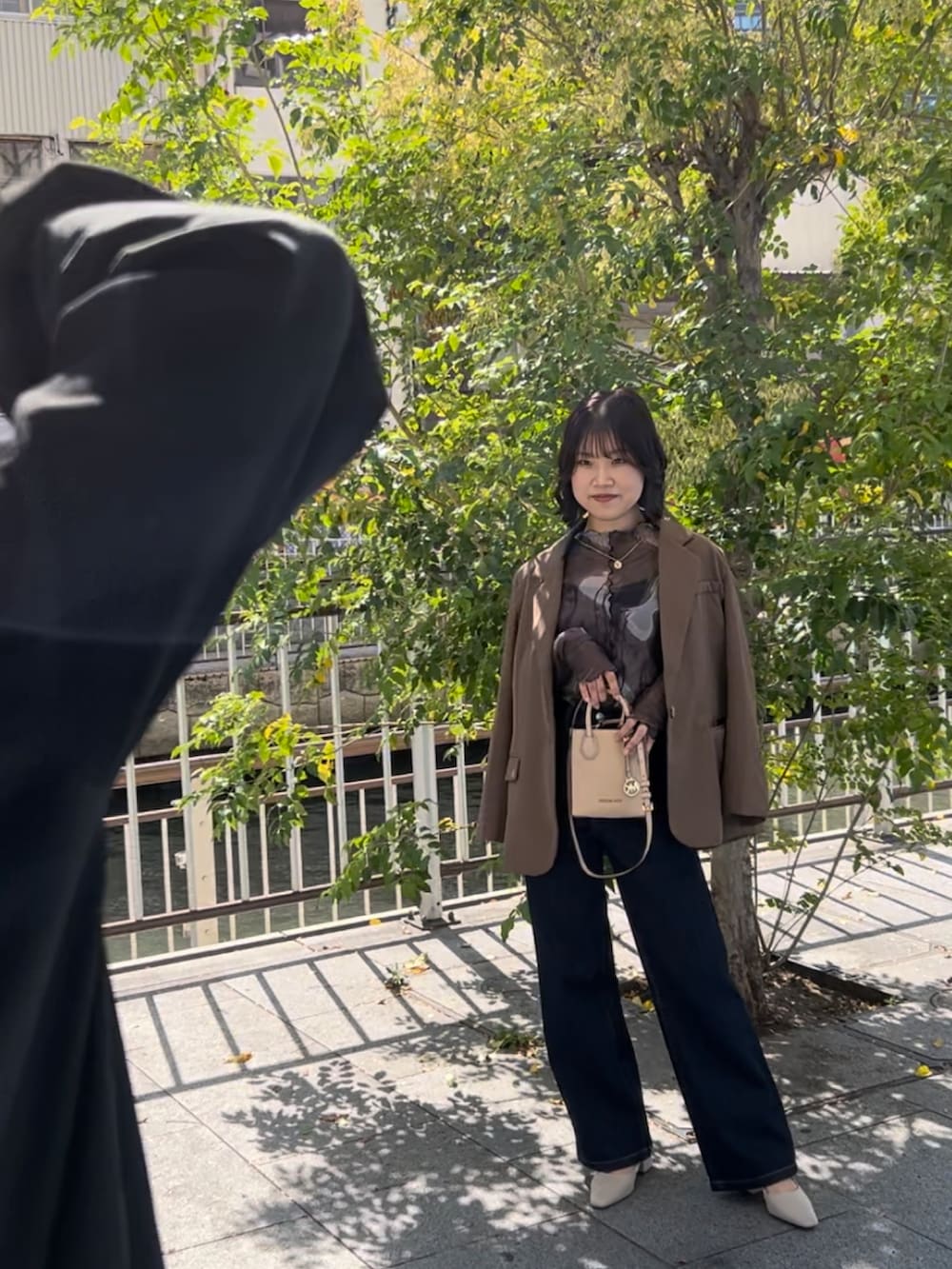 ブルー系のデニムパンツ、ブラック系のパンプス、グリーン系のTシャツ/カットソーを着用したレディースの秋コーディネートの3枚目の写真