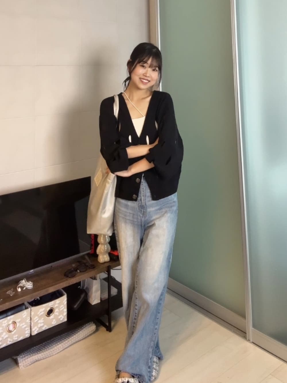 ブルー系のデニムパンツ、ブラック系のカーディガン/ボレロ、ホワイト系のキャミソールを着用したレディースの秋コーディネートの2枚目の写真