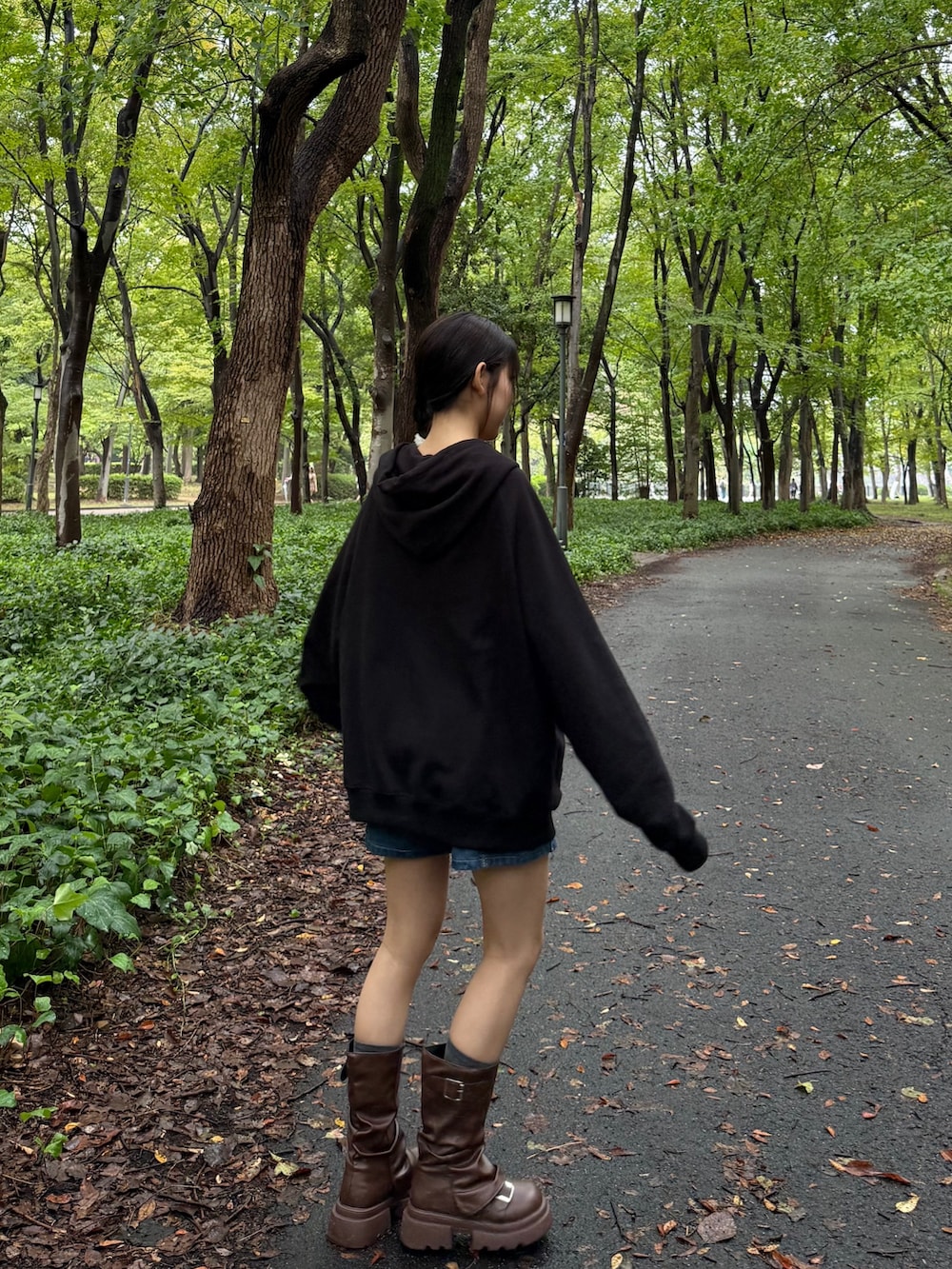 ブラウン系のブーツ、ブラック系のパーカー、ブルー系のデニムパンツを着用したレディースの秋コーディネートの2枚目の写真