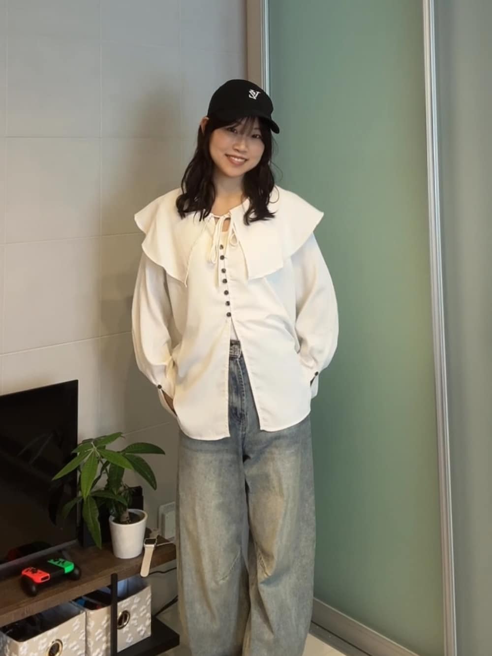 ホワイト系のシャツ/ブラウス、ブルー系のデニムパンツ、ブラック系のキャップを着用したレディースの夏コーディネートの2枚目の写真