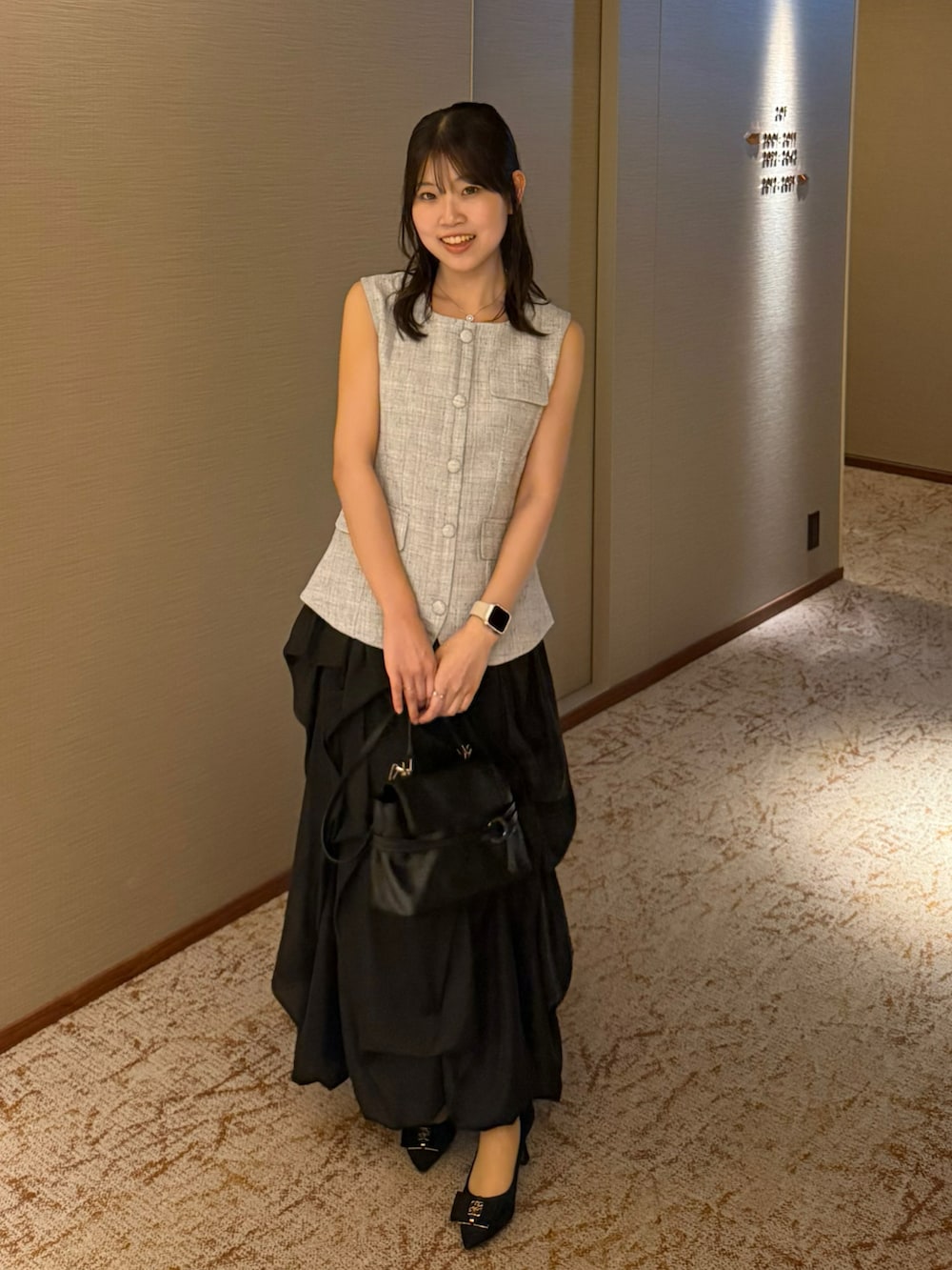 ブルー系のトップス、ブラック系のショルダーバッグ、ブラック系のスカートを着用したレディースの夏コーディネートの2枚目の写真