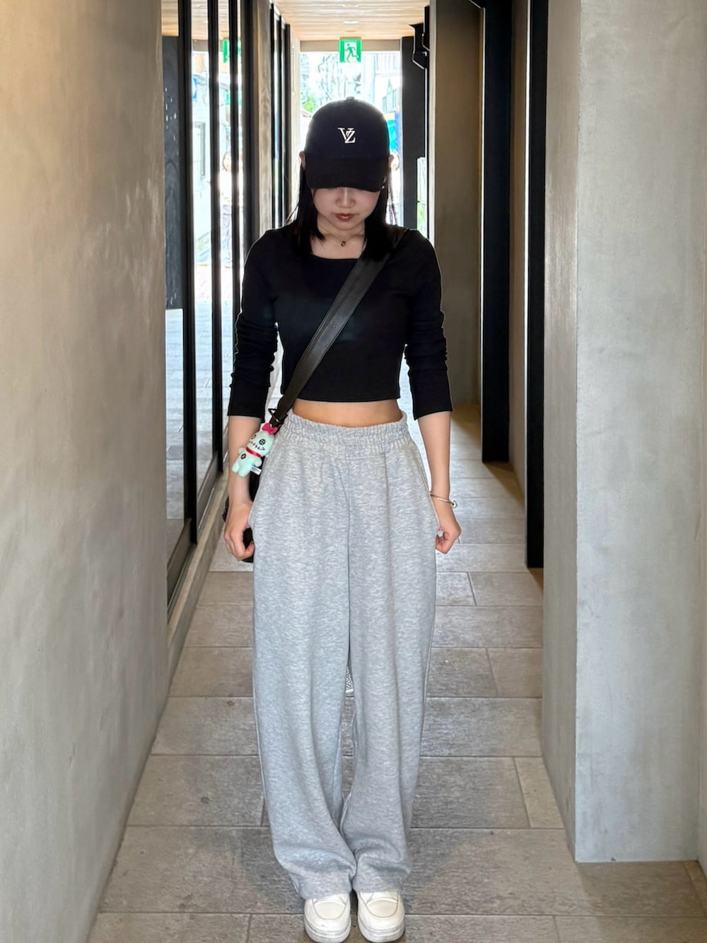 グレー系のスウェットパンツ、ホワイト系のスニーカー、ブラック系のトップスを着用したレディースの春コーディネートの2枚目の写真