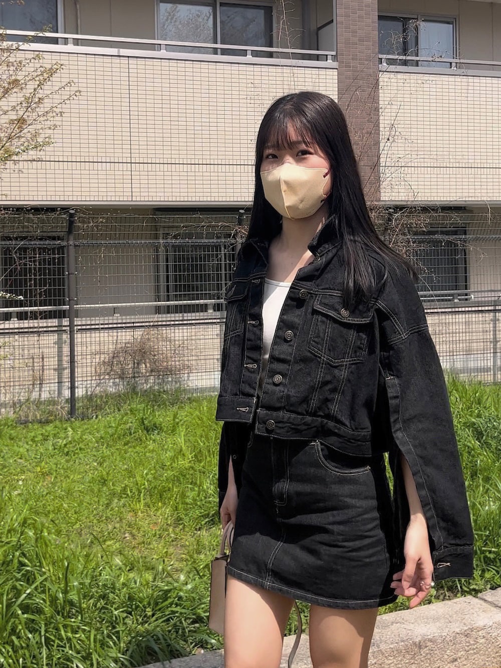 ベージュ系のショルダーバッグ、ブラック系のデニムジャケット、ブラック系のデニムスカートを着用したレディースの春コーディネートの5枚目の写真