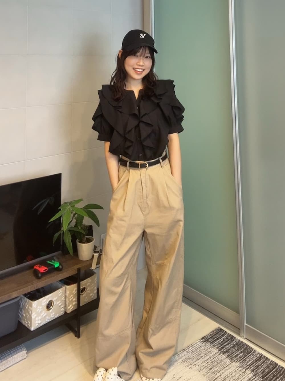 ブラック系のシャツ/ブラウス、ベージュ系のパンツ、ブラック系のキャップを着用したレディースの夏コーディネートの2枚目の写真