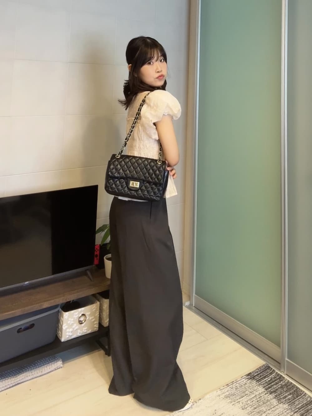 ピンク系のシャツ/ブラウス、グレー系のスラックス、ブラック系のショルダーバッグを着用したレディースの春コーディネートの2枚目の写真