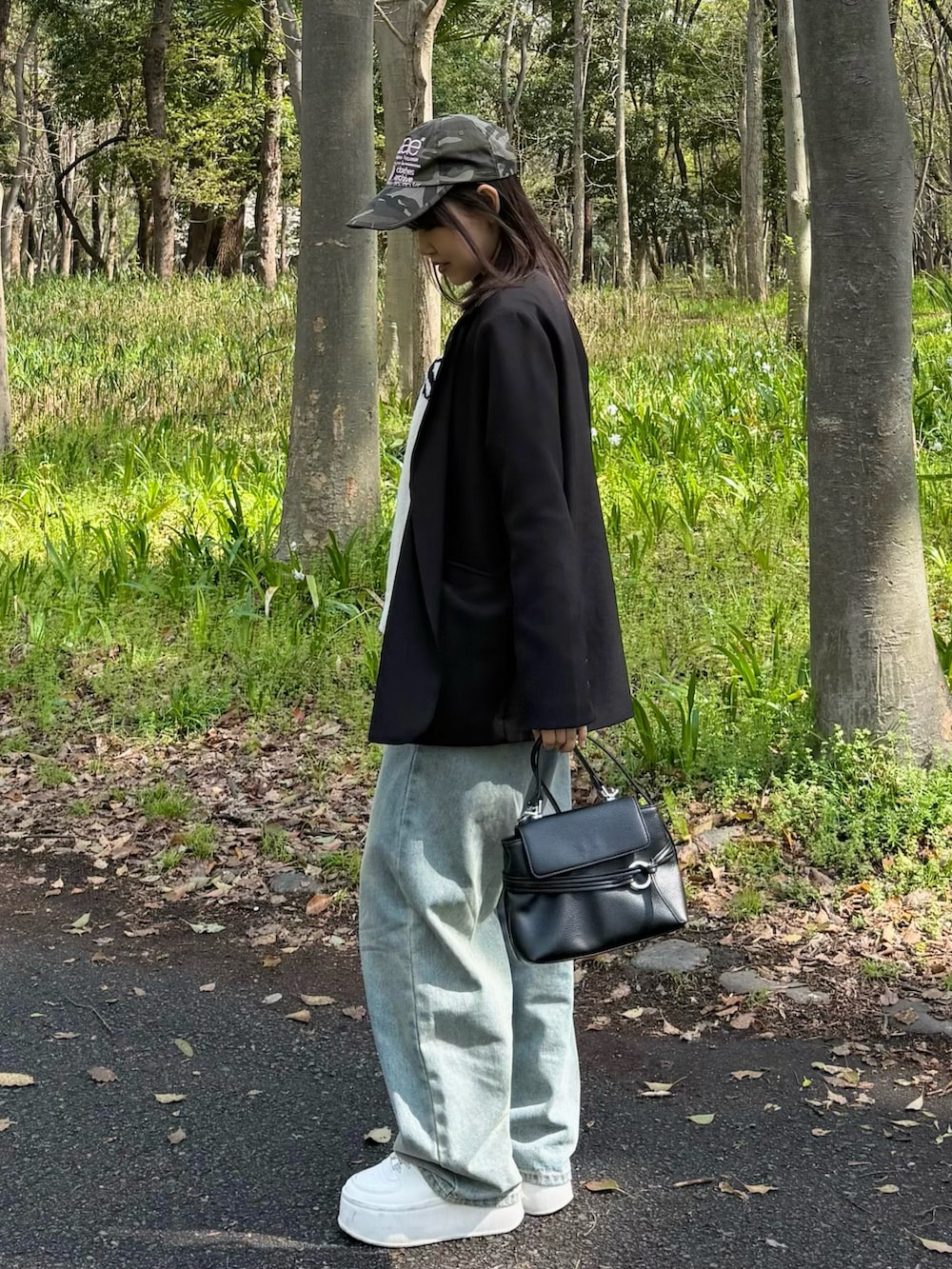 ブラック系のテーラードジャケット、ホワイト系のニット/セーター、ブラック系のショルダーバッグを着用したレディースの春コーディネートの2枚目の写真