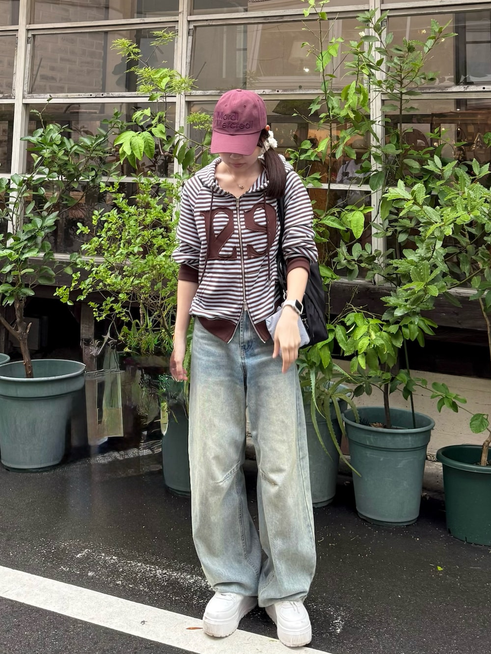 ブルー系のデニムパンツ、ホワイト系のスニーカー、ブラック系のトートバッグを着用したレディースの秋コーディネートの2枚目の写真
