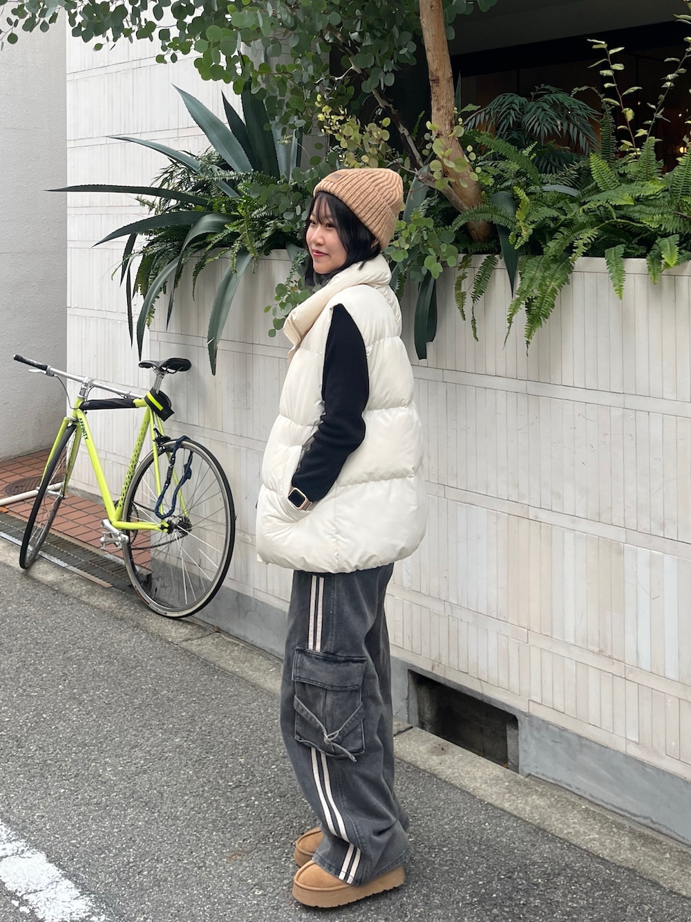 ブラック系のデニムパンツ、ベージュ系のブーツ、ホワイト系のダウンベストを着用したレディースの冬コーディネートの2枚目の写真