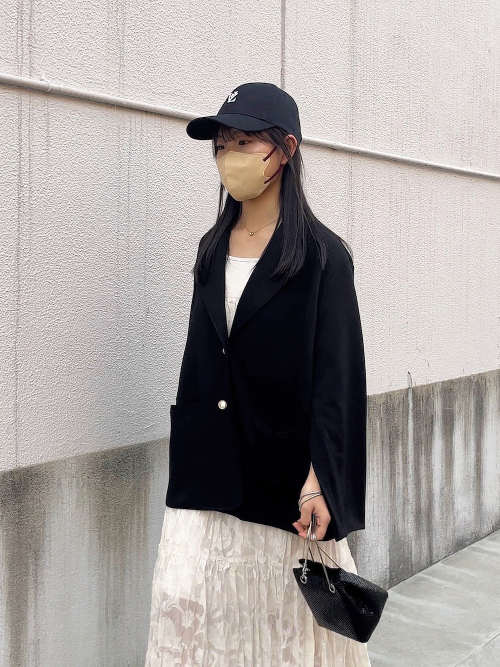 ブラック系のテーラードジャケット、ホワイト系のワンピース、ブラック系のショルダーバッグを着用したレディースの春コーディネートの4枚目の写真