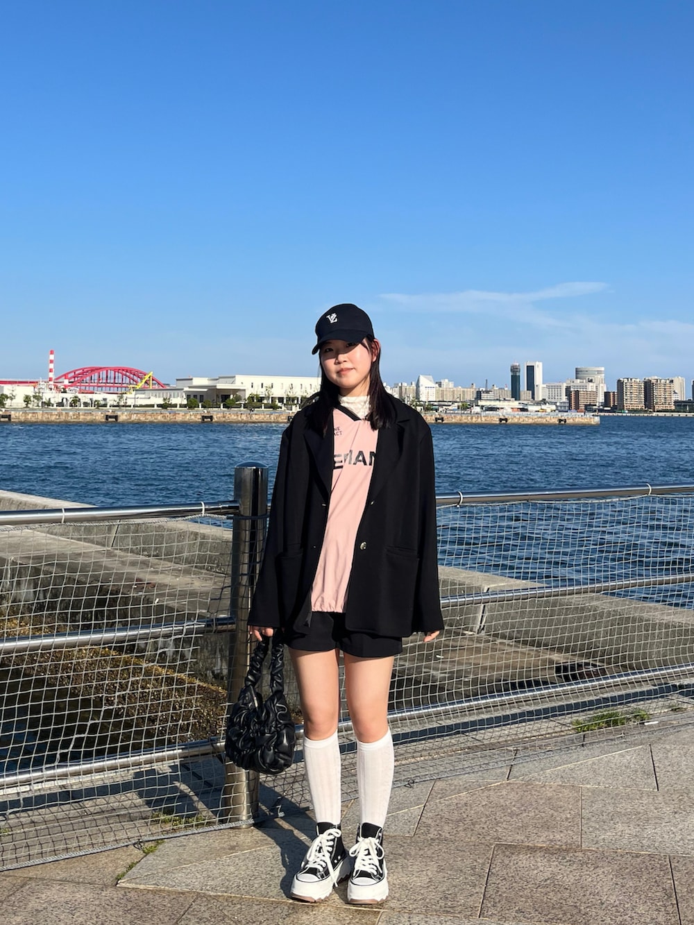 ブラック系のテーラードジャケット、ピンク系のその他トップス、ブラック系のシューズを着用したレディースの春コーディネートの2枚目の写真