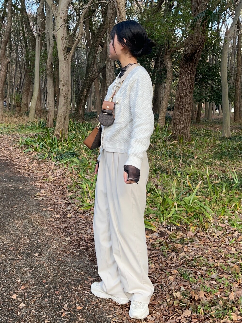 ホワイト系のスラックス、ホワイト系のスニーカー、ブラウン系のボディバッグ/ウエストポーチを着用したレディースの冬コーディネートの2枚目の写真