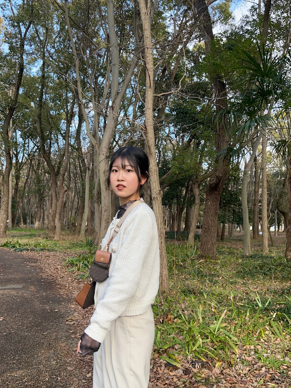 ホワイト系のスラックス、ホワイト系のスニーカー、ブラウン系のボディバッグ/ウエストポーチを着用したレディースの冬コーディネートの4枚目の写真