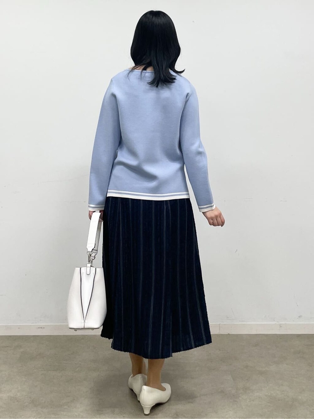 ブルー系のニット/セーター、ブルー系のスカート、ベージュ系のその他アウターを着用したレディースの冬コーディネートの10枚目の写真