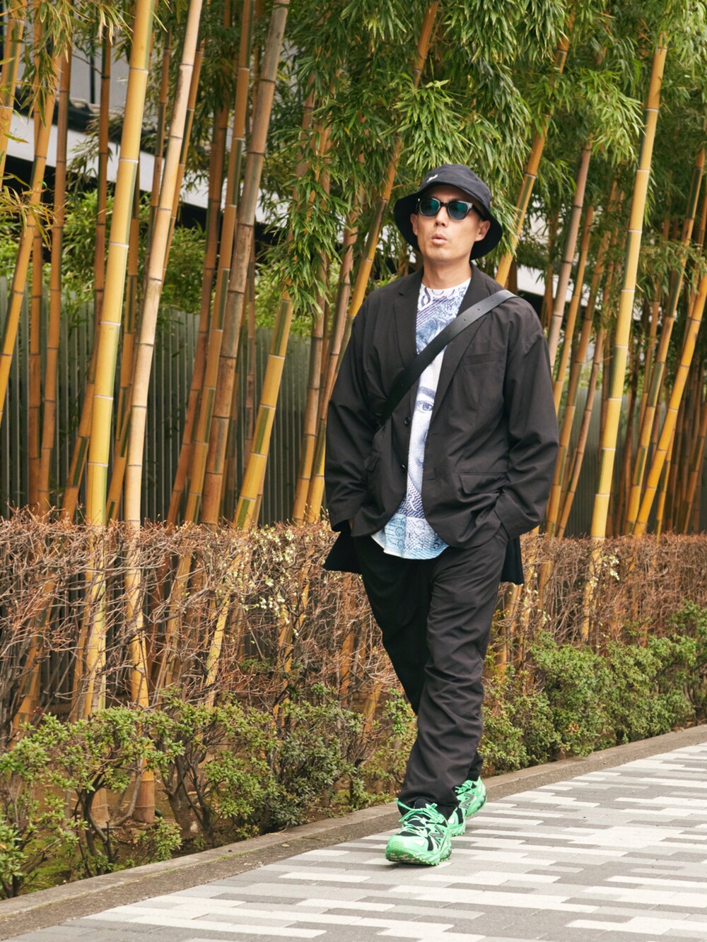 グリーン系のスニーカー、ブラック系のバッグ、ブラック系のハットを着用したメンズの春コーディネートの2枚目の写真